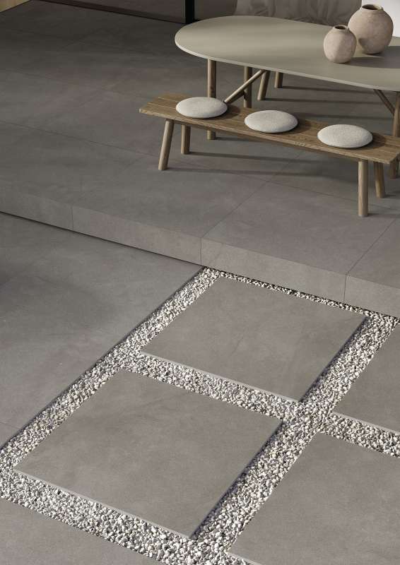 Hochwertige graue Outdoor-Fliesen mit Kiesfugen auf einer modernen Terrasse.